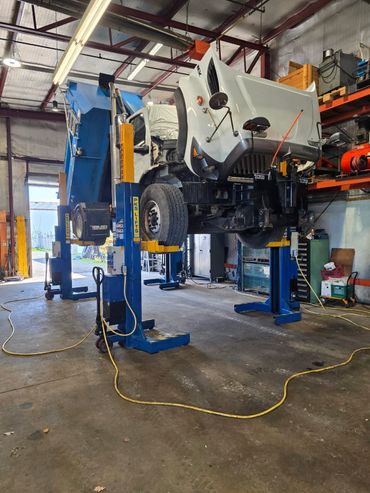 A large dump truck lifted inside a repair shop for maintenance.