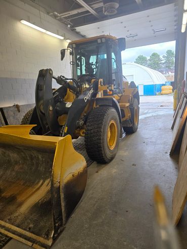 Yellow John Deere front loader inside a garage.