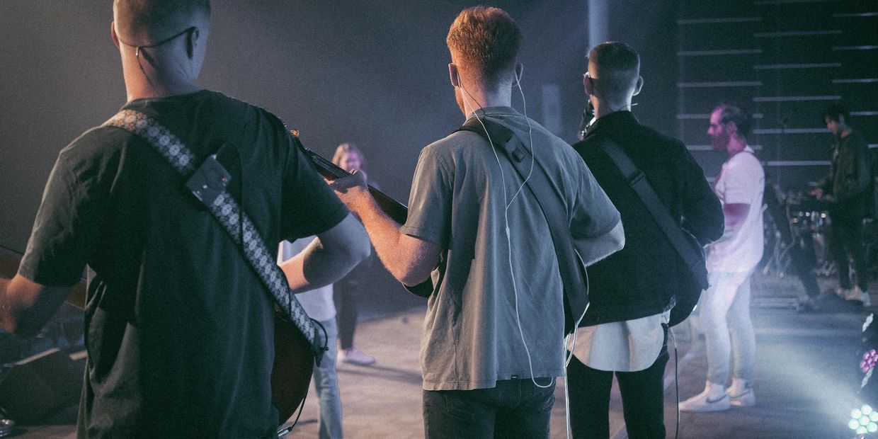 Musicians playing guitars on stage during a live performance.