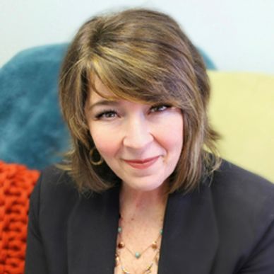 Smiling woman in a black blazer and necklace.