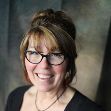 Smiling woman wearing glasses with a blurred background.