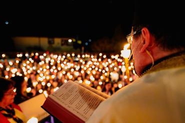 A speaker reads from a book during a candlelight vigil at night.