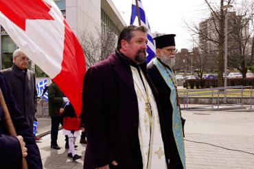 Religious figures walking with flags outdoors.