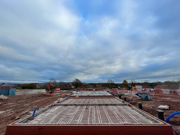 Construction site with foundation slabs under a cloudy sky.