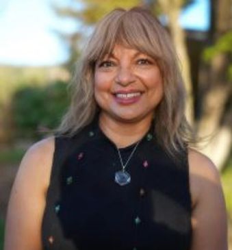 Smiling woman with blonde hair outdoors.