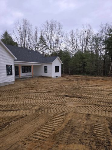 Newly constructed house with freshly cleared and leveled yard showing tire tracks.