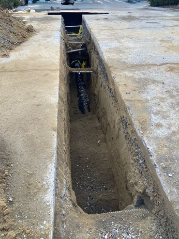 A deep trench dug in the ground for utilities or construction work.