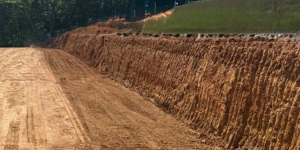 Excavated dirt slope alongside a cleared construction path.