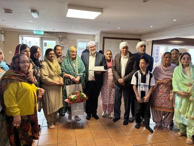 A group of people posing indoors, some holding flowers and gifts.