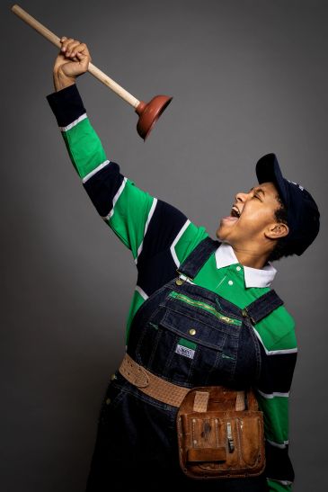 Person enthusiastically holding a plunger up high.