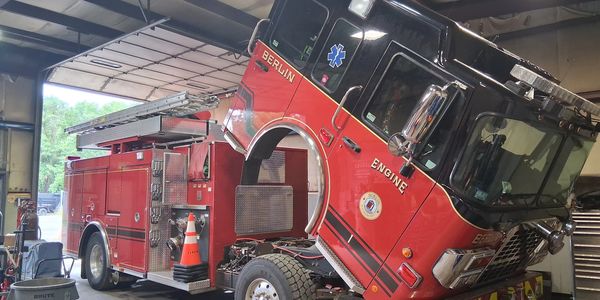 Fire truck cab tilted forward for engine maintenance inside a garage.