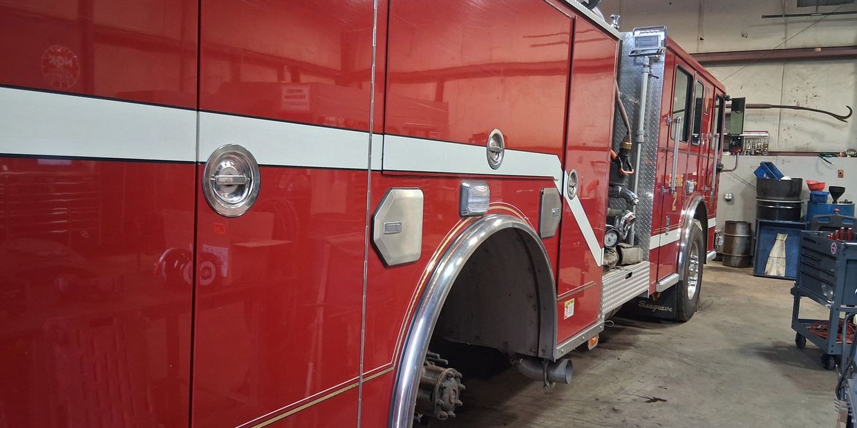 A large red fire truck inside a garage without front wheel.