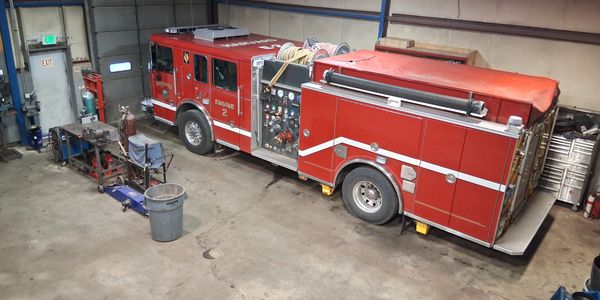 A red fire engine parked inside a spacious garage with maintenance equipment.