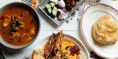 A table with various dishes including curry, prawns, and flatbread.