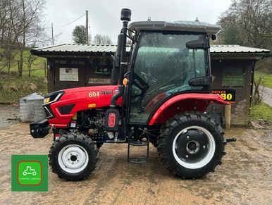 Red Case IH 604 tractor parked in front of a rustic building.