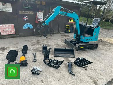 Mini excavator with various attachments laid out on the ground.