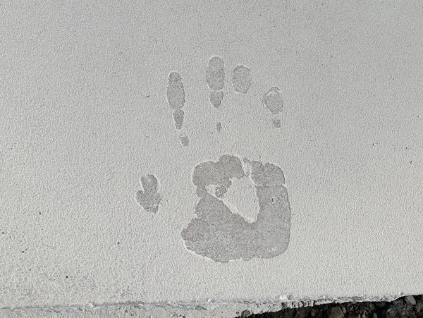 Handprint impression on wet concrete slab.