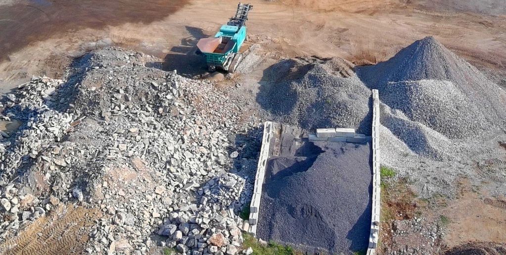 Construction site with piles of gravel and machinery.