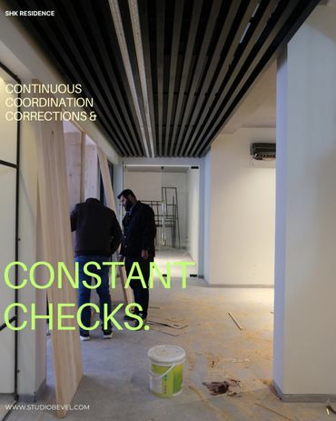Two men inspecting wood panels in a modern unfinished interior space.
