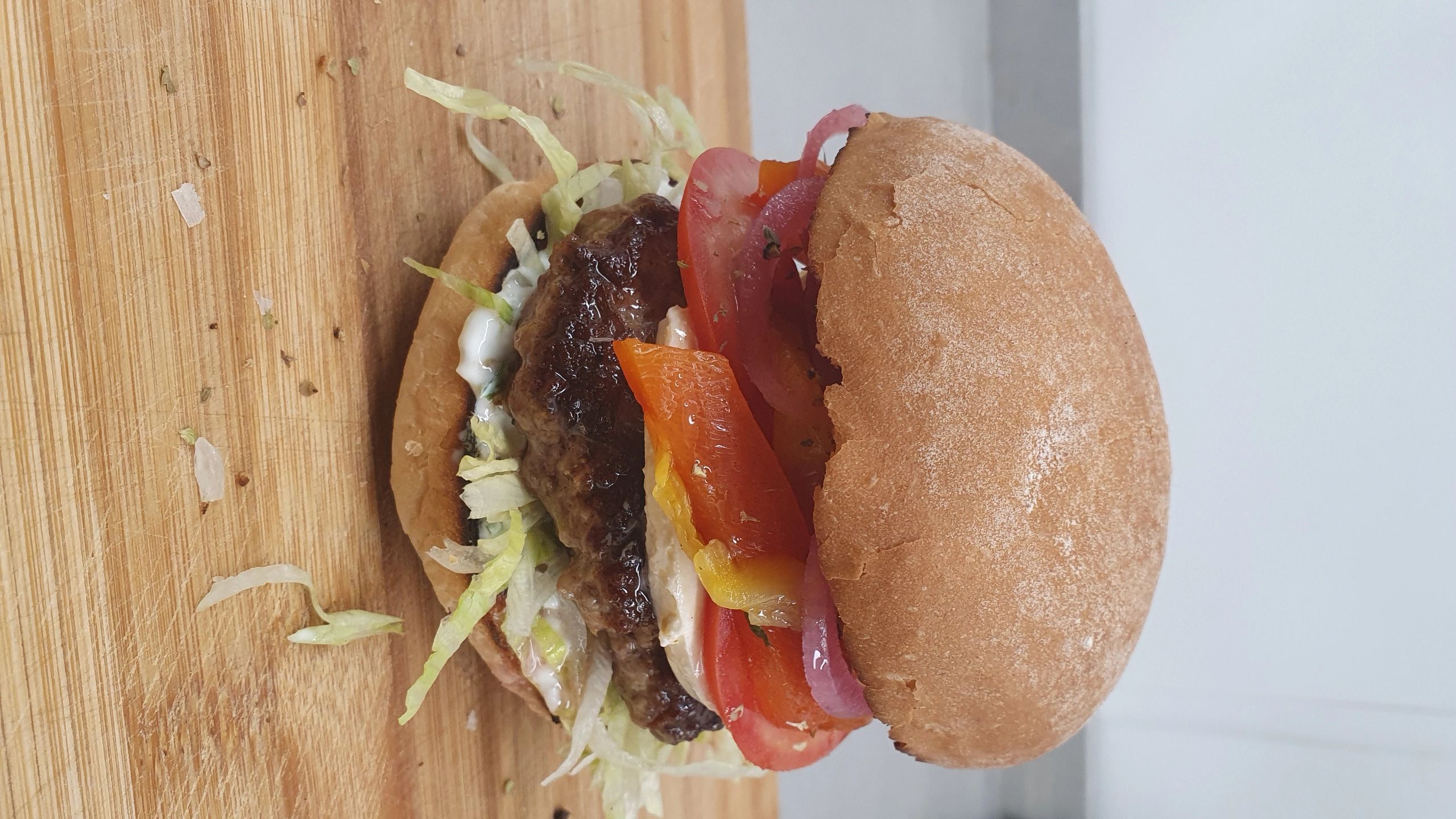 Juicy hamburger with fresh vegetables on wooden board.