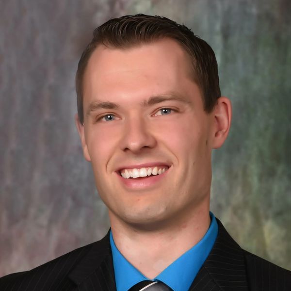 Smiling man in suit and blue shirt.