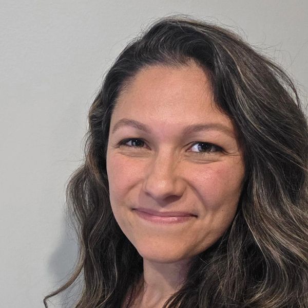 Smiling woman with long wavy hair.