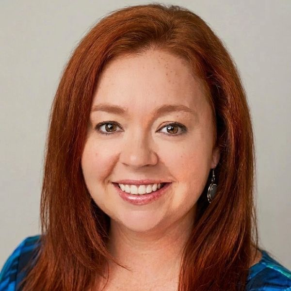 Smiling woman with red hair and earrings.