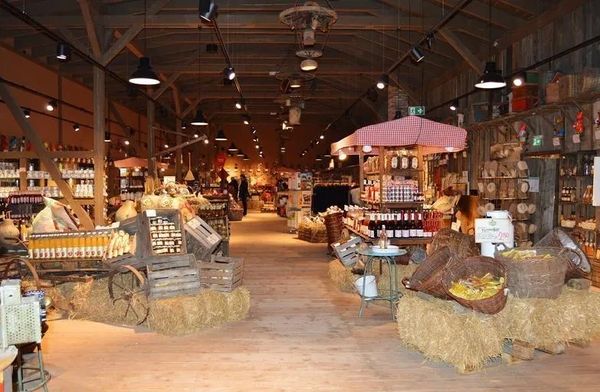 Rustic indoor market with wooden beams and hay displays.