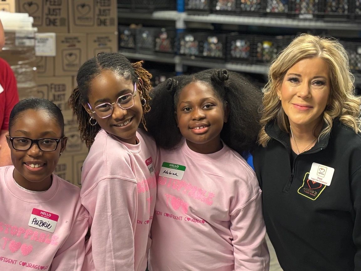 Group of smiling girls and a woman in a warehouse.