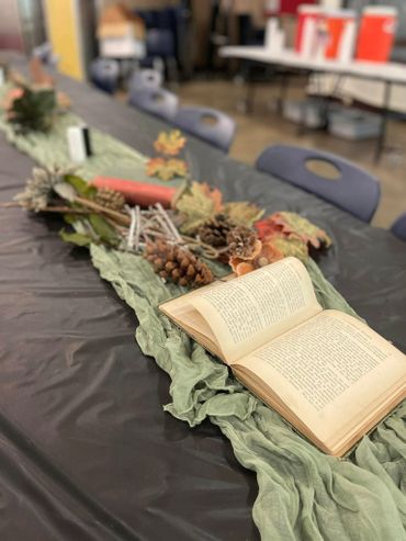 An open book on a rustic autumn-themed table centerpiece.