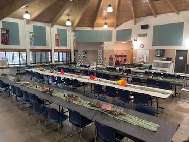 A large hall with long tables decorated for an event or gathering.