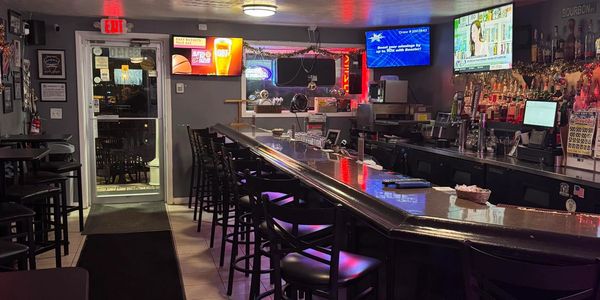 Empty bar with high chairs and TV screens.