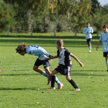 Young soccer players competing intensely on the field during a sunny day.