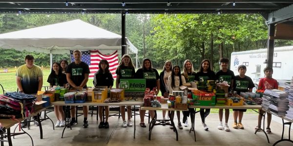Group of young people with school supplies under a shelter.