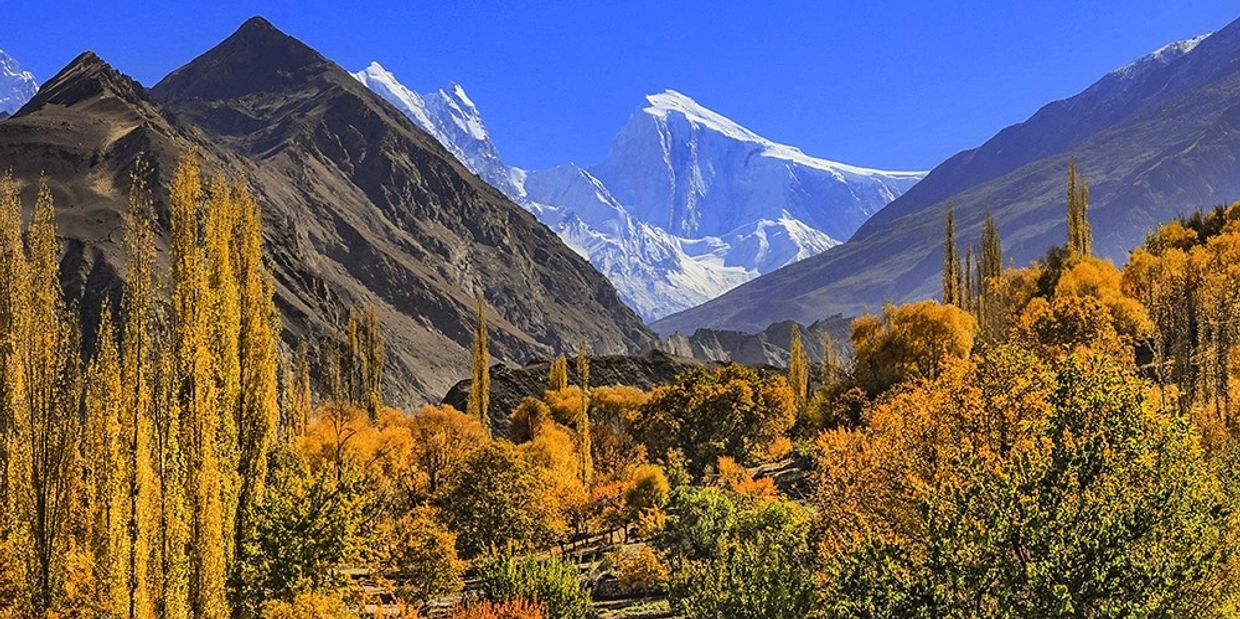 Beautiful autumnal image of Northern Pakistan with backdrop of snow capped mountains