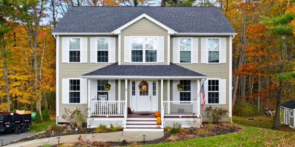 Two-story house with fall decorations and autumn trees.