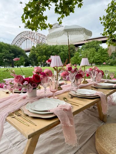 Elegant pink-themed outdoor dining setup with flowers and umbrella.