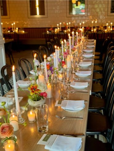 Elegantly set long dining table with candles and flowers.