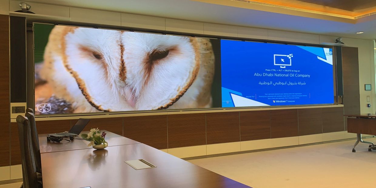 Meeting room with a large screen showing an owl and a login screen.