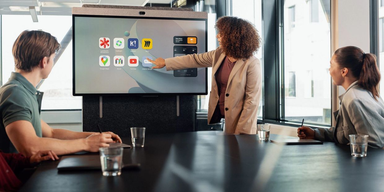 Mujer realizando una presentación en un monitor táctil NEAT en una sala de reuniones. 