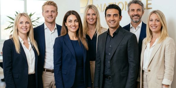 Seven professionals in business attire posing together indoors.