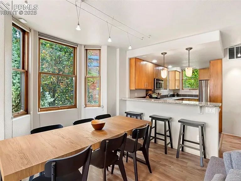 Modern kitchen and dining area with wooden table, black chairs, and large windows.
