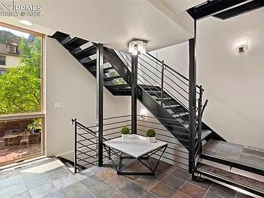 Modern black metal staircase with a glass window and small table.