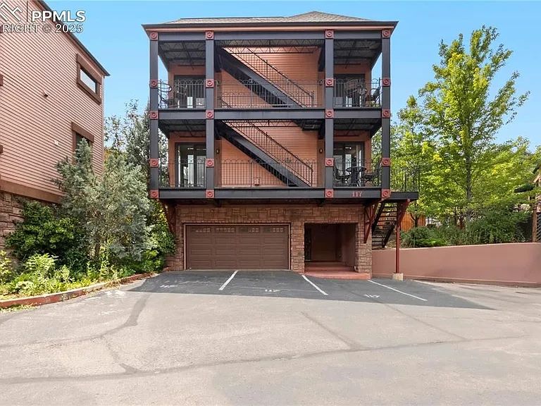 Modern three-story building with external staircases and parking spaces in front.