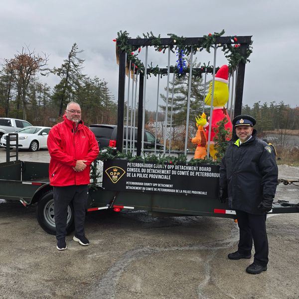 Two men stand by a decorated police float outdoors.
