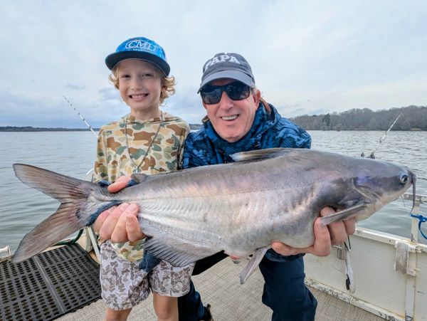 Man and child holding a large fish on a boat.