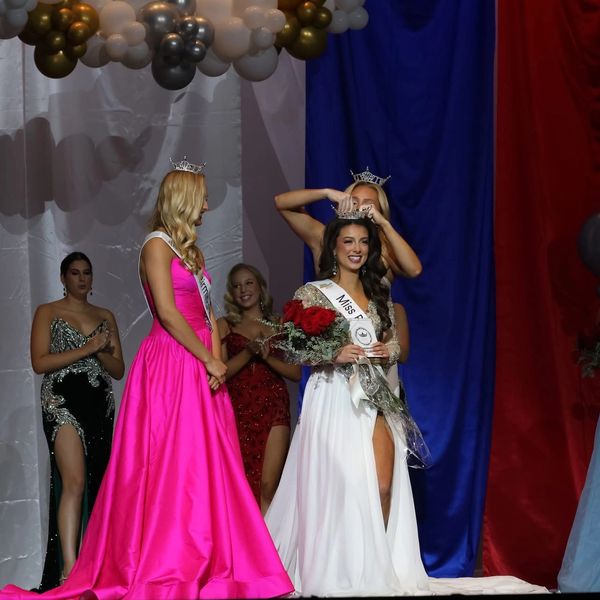 Newly crowned beauty queen beams with joy as she receives her crown and bouquet.