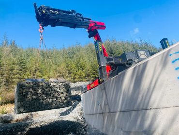 Crane lifting a heavy load of stones at a construction site.