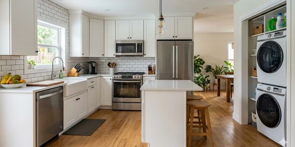 Modern kitchen with white cabinetry, stainless steel appliances, and wooden flooring.