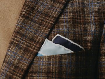 Close-up of blue pocket square in a brown plaid jacket pocket